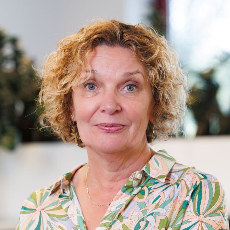 Jacqueline in een kleurrijke blouse op kantoor