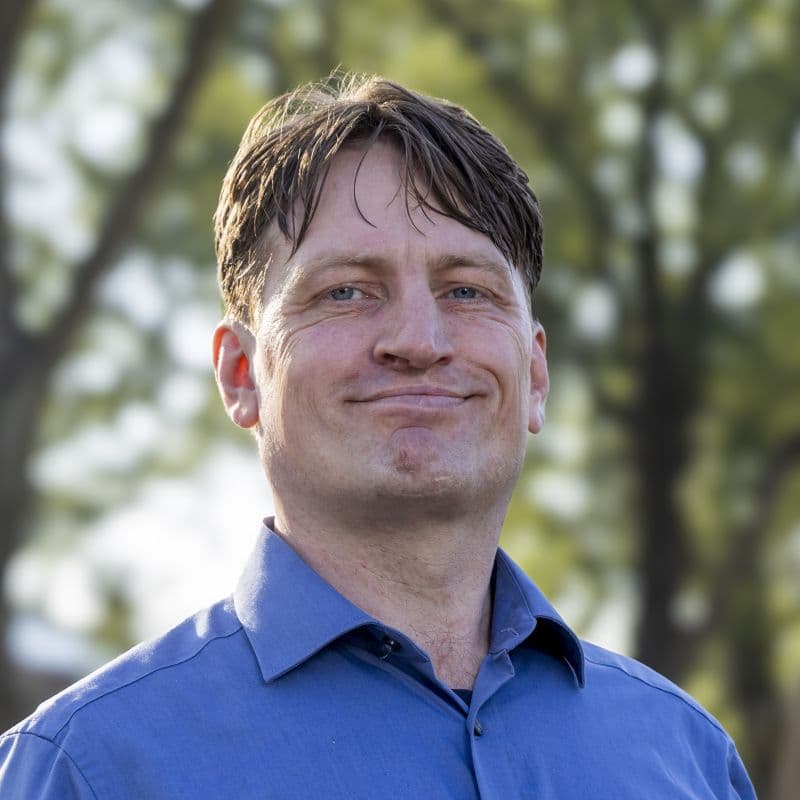 Jelle in een blauwe overhemd met een groenrijke achtergrond