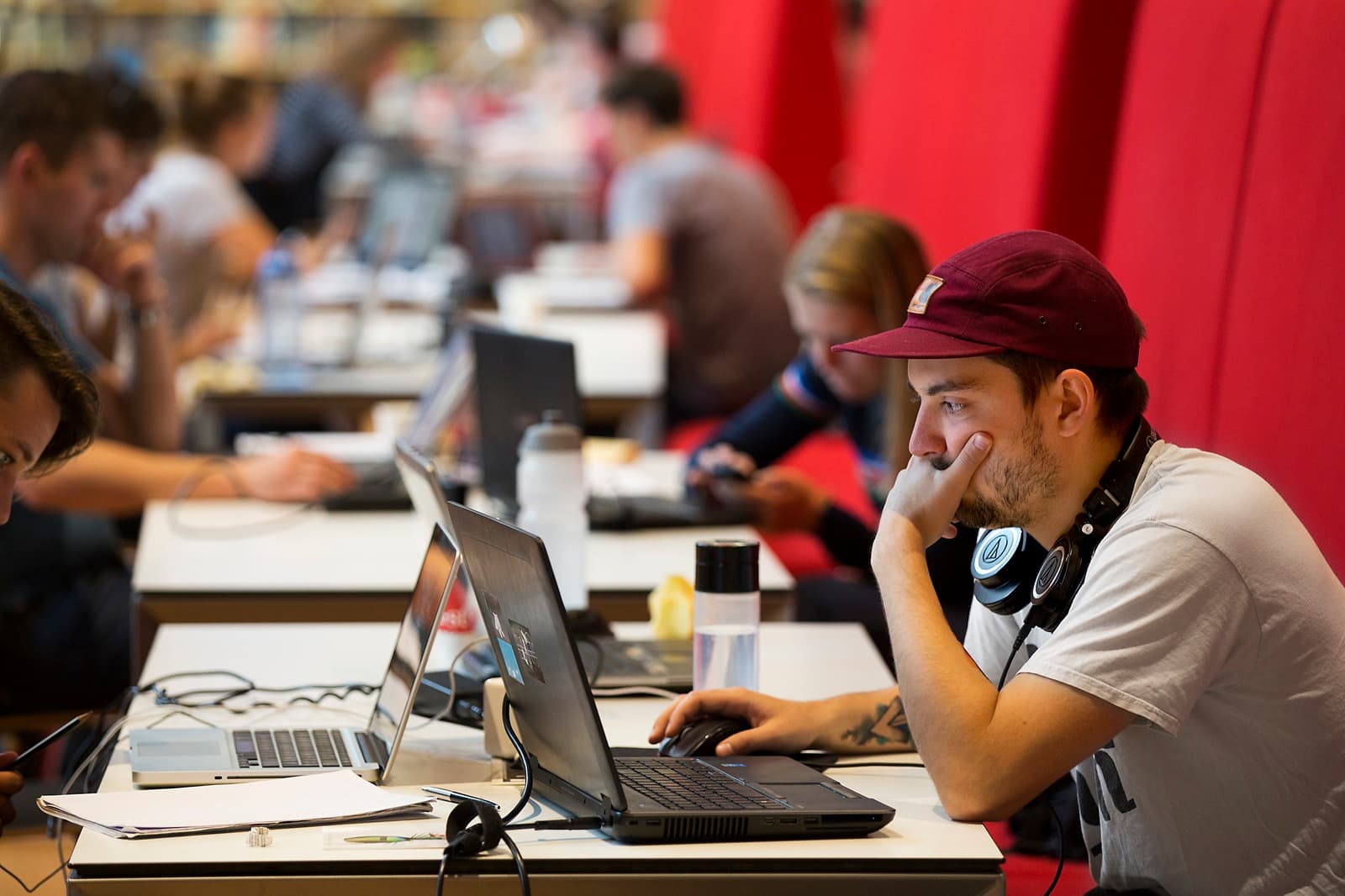 Jongen aan het studeren achter laptop in bibliotheek